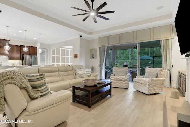 living area featuring recessed lighting, a tray ceiling, a ceiling fan, light wood-style flooring, and ornamental molding