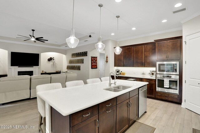 kitchen featuring appliances with stainless steel finishes, ornamental molding, a sink, a ceiling fan, and a kitchen breakfast bar