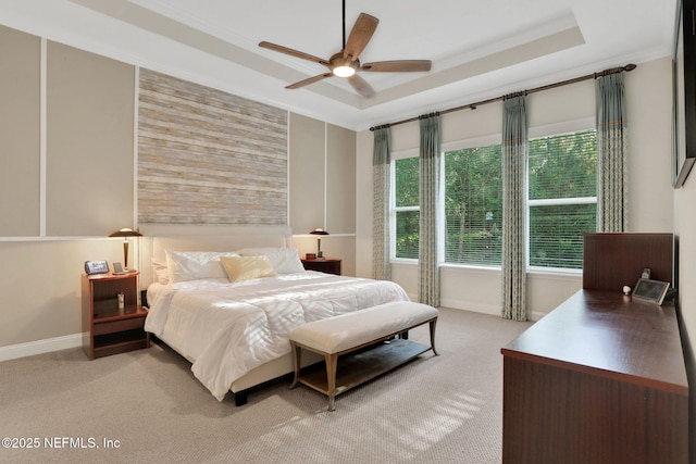 bedroom with ceiling fan, a tray ceiling, crown molding, light carpet, and baseboards