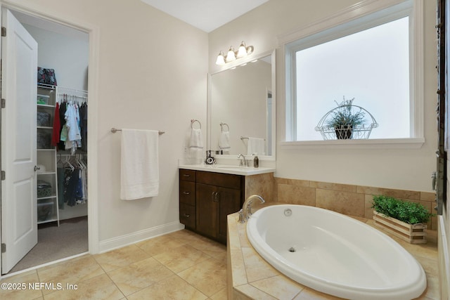 full bathroom with tile patterned floors, a bath, vanity, baseboards, and a spacious closet