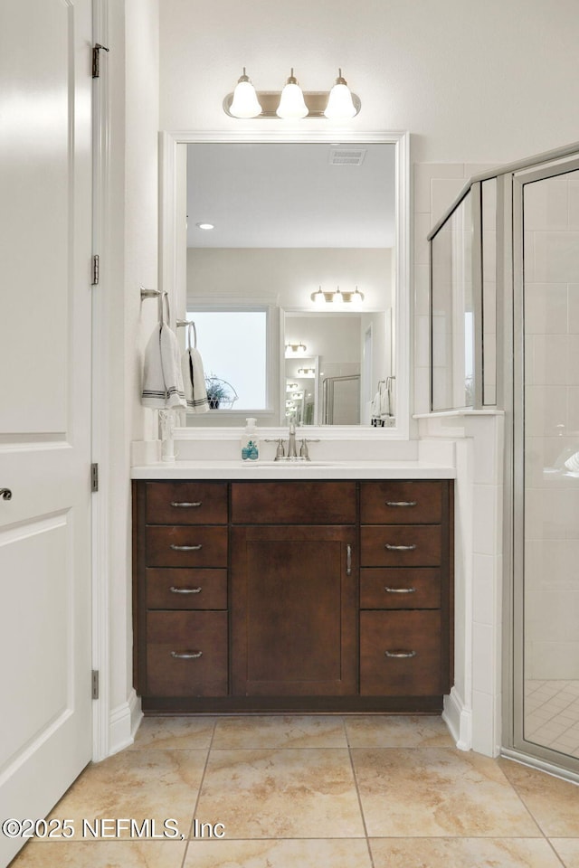 bathroom with vanity, a shower stall, visible vents, and tile patterned flooring