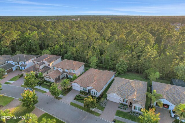 drone / aerial view featuring a wooded view and a residential view