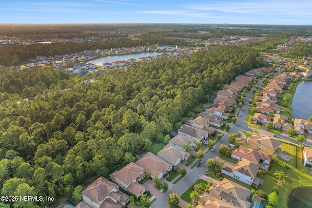 drone / aerial view with a water view, a forest view, and a residential view