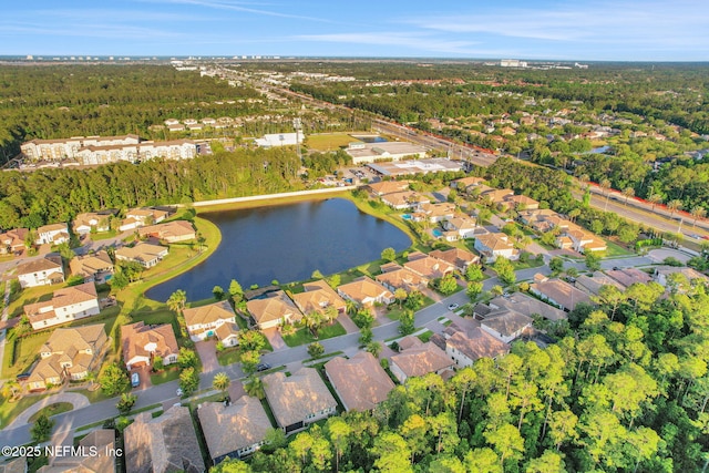 aerial view featuring a water view, a view of trees, and a residential view