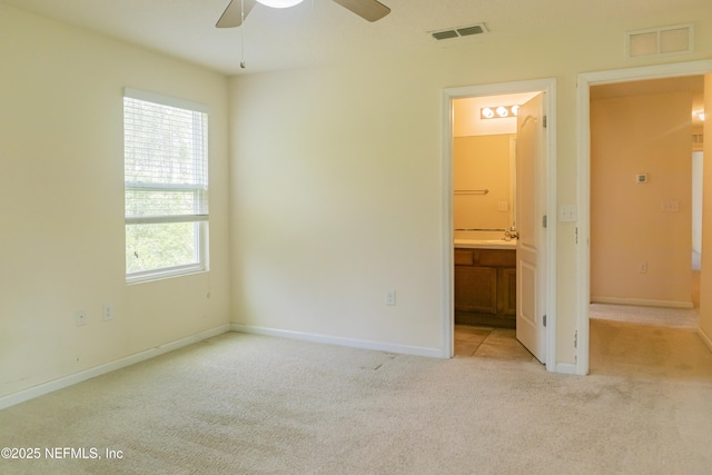 unfurnished bedroom featuring carpet floors, baseboards, ensuite bath, and visible vents