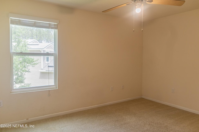 carpeted spare room with a ceiling fan and baseboards