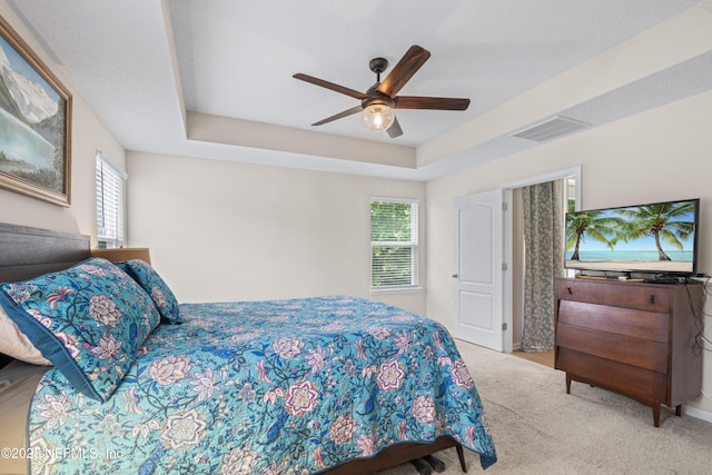bedroom with ceiling fan, a raised ceiling, carpet, and visible vents