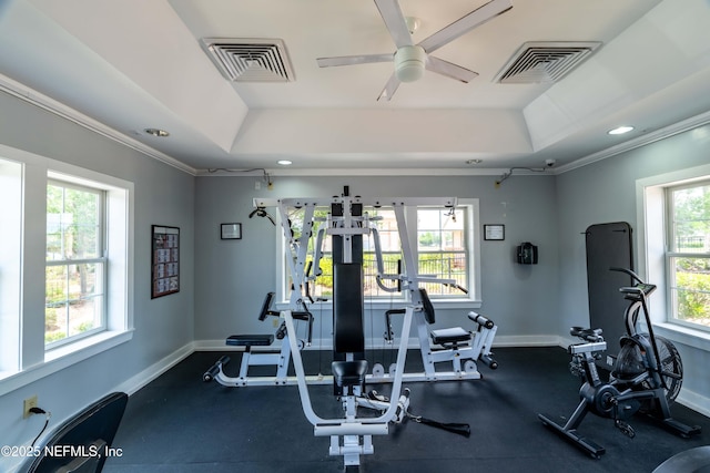 exercise room with a tray ceiling, baseboards, and visible vents