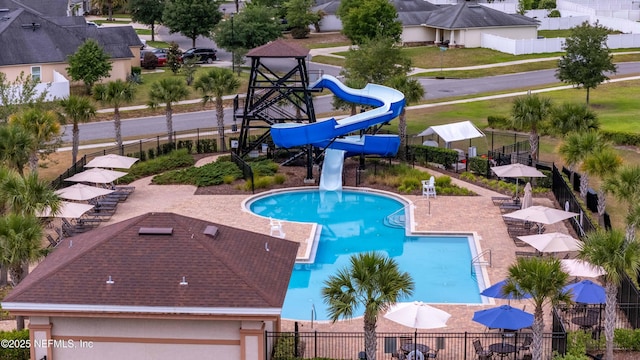 community pool featuring a water slide and fence