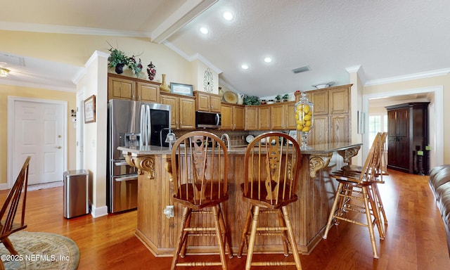 4637 Saddlehorn Trl, Middleburg, FL 32068 - kitchen with appliances with stainless steel finishes, light wood finished floors, a kitchen bar, brown cabinets, and backsplash