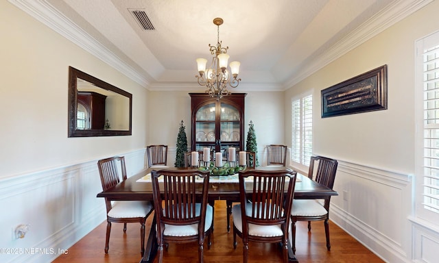 4637 Saddlehorn Trl, Middleburg, FL 32068 - dining space with a chandelier, a wainscoted wall, crown molding, a raised ceiling, and wood finished floors
