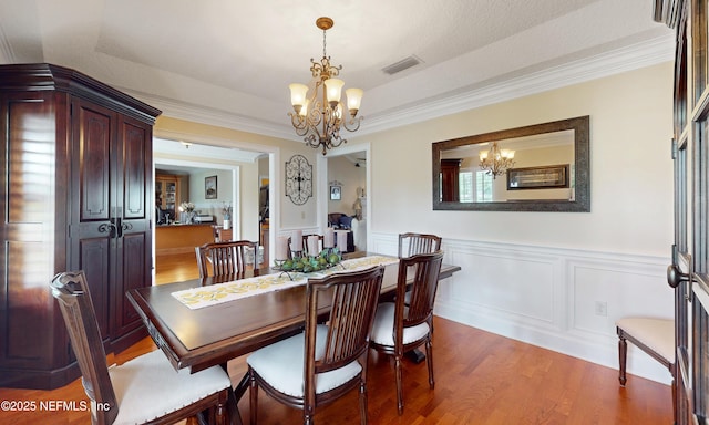 4637 Saddlehorn Trl, Middleburg, FL 32068 - dining room with a chandelier, light wood-style flooring, wainscoting, and ornamental molding