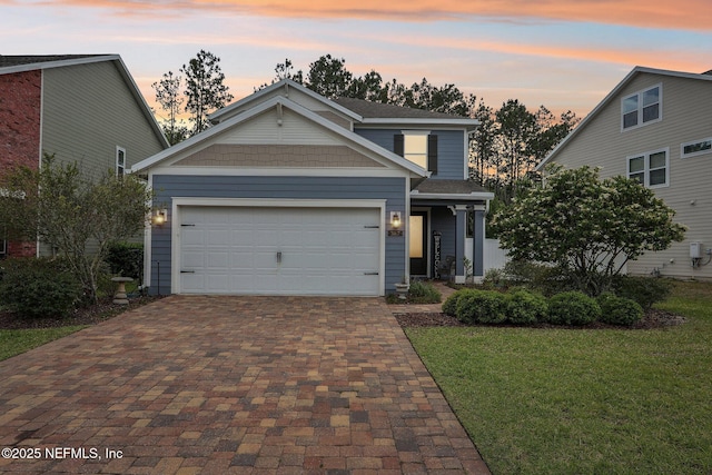 traditional home featuring a front lawn, decorative driveway, and an attached garage
