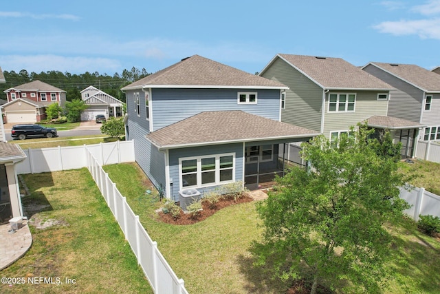 back of house featuring a sunroom, a lawn, a fenced backyard, and roof with shingles