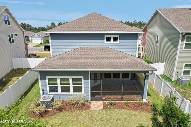 back of property featuring a sunroom, a lawn, a shingled roof, and central AC unit