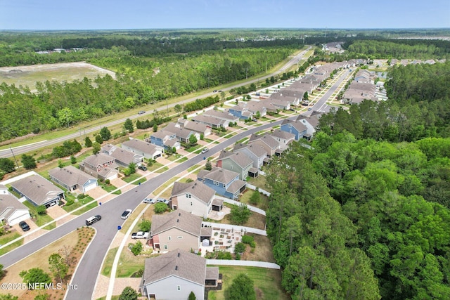 drone / aerial view featuring a residential view and a wooded view