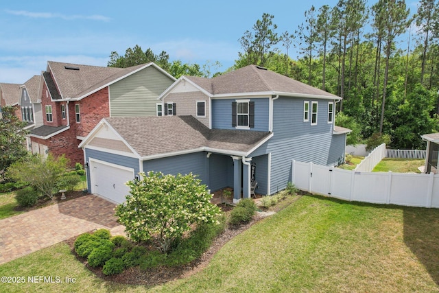 view of front of home with decorative driveway, a front yard, a shingled roof, and fence