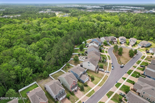 drone / aerial view with a wooded view and a residential view