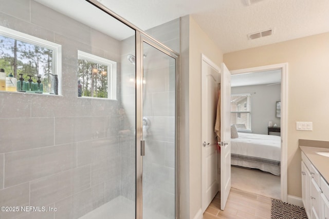 ensuite bathroom featuring a stall shower, ensuite bath, vanity, and plenty of natural light