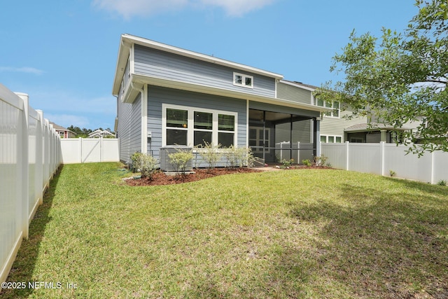 rear view of house featuring a lawn, a fenced backyard, and a sunroom