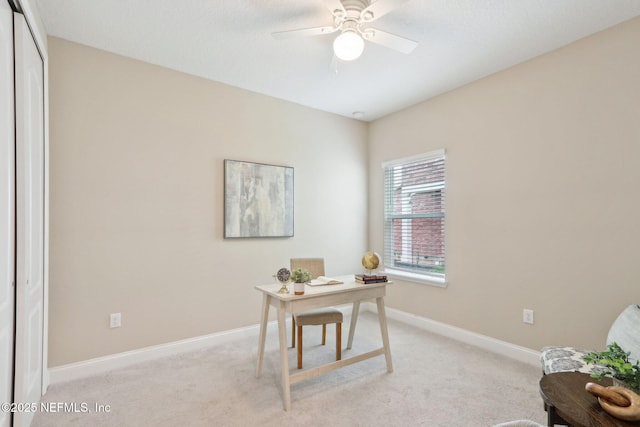 office space with a ceiling fan, light carpet, and baseboards