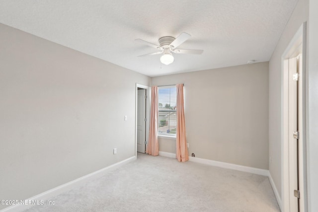 unfurnished room with light colored carpet, ceiling fan, a textured ceiling, and baseboards