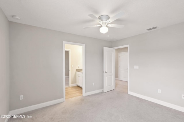 unfurnished bedroom with ceiling fan, ensuite bath, visible vents, baseboards, and light colored carpet