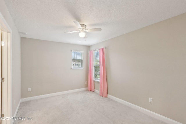 empty room with baseboards, light carpet, ceiling fan, and a textured ceiling