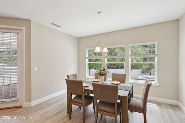 dining space with an inviting chandelier, visible vents, a wealth of natural light, and light wood-type flooring