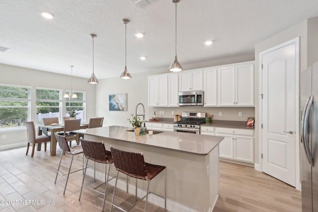 kitchen featuring recessed lighting, a sink, a kitchen bar, light wood-type flooring, and appliances with stainless steel finishes