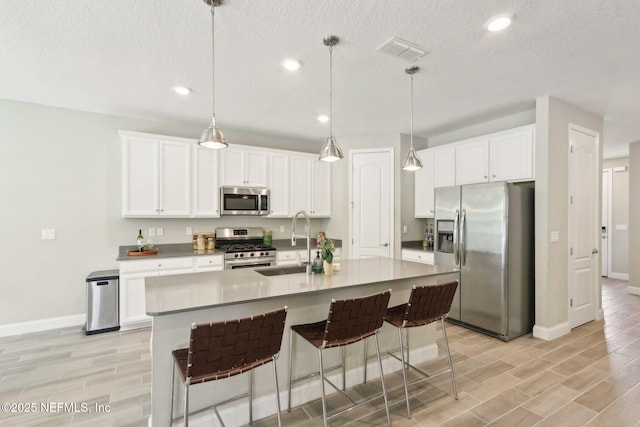 kitchen with wood tiled floor, a sink, appliances with stainless steel finishes, and baseboards
