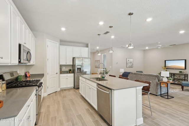 kitchen featuring a ceiling fan, a sink, stainless steel appliances, and light wood-type flooring