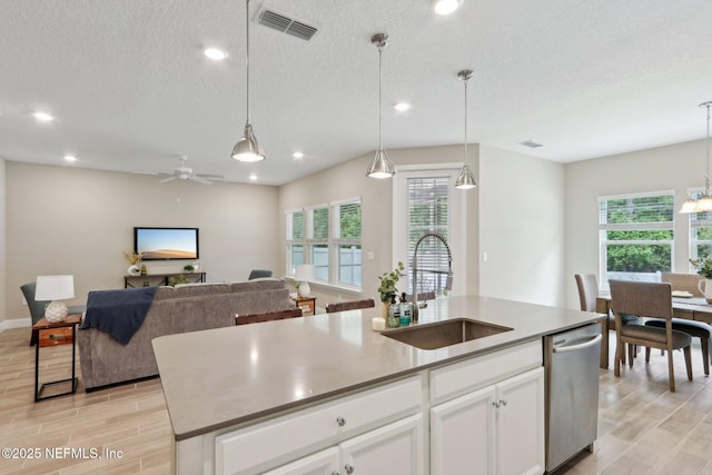 kitchen featuring recessed lighting, an island with sink, dishwasher, a sink, and visible vents