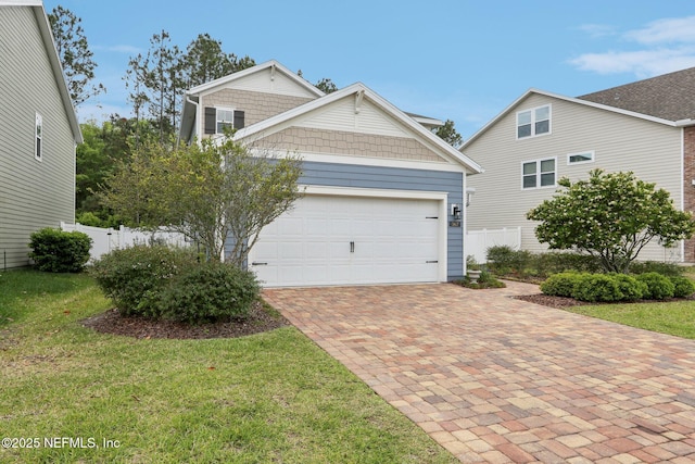 traditional-style home with a front lawn, fence, decorative driveway, and a garage