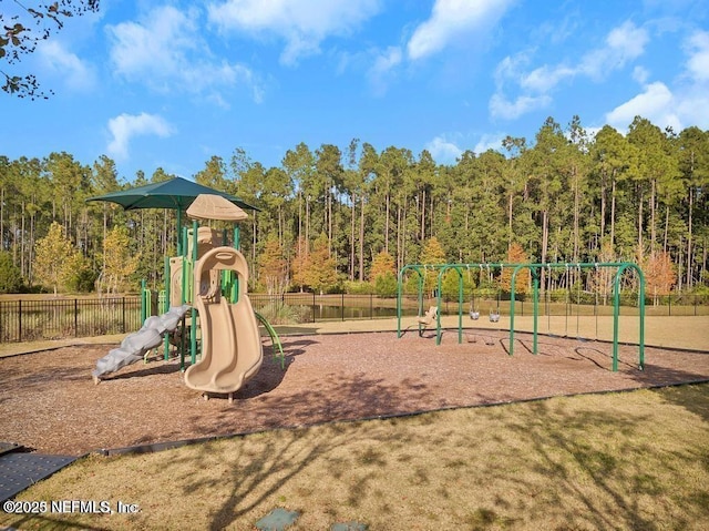 communal playground featuring a forest view and fence