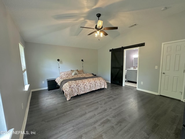 bedroom featuring dark wood-style flooring, visible vents, vaulted ceiling, a barn door, and baseboards