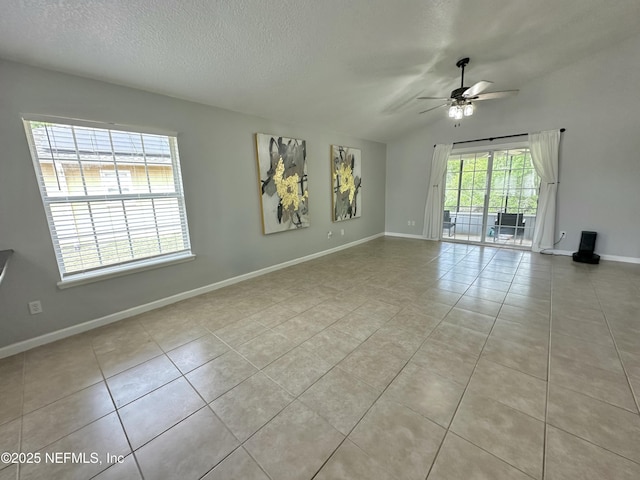 tiled spare room with a textured ceiling, ceiling fan, and baseboards