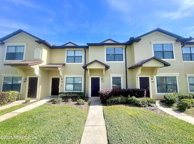 view of property featuring stucco siding and a front yard