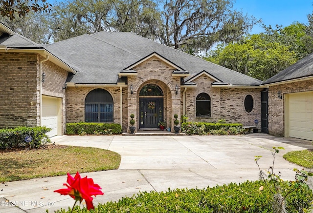 view of front of home featuring driveway, roof with shingles, and brick siding