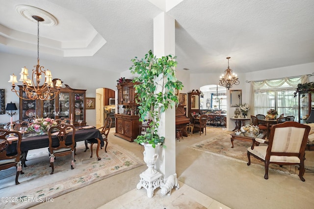 dining room with an inviting chandelier, a textured ceiling, carpet flooring, and arched walkways