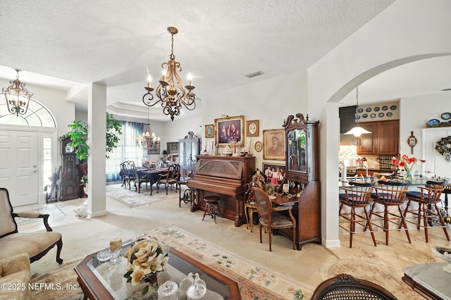 dining space with an inviting chandelier, visible vents, a textured ceiling, light carpet, and arched walkways