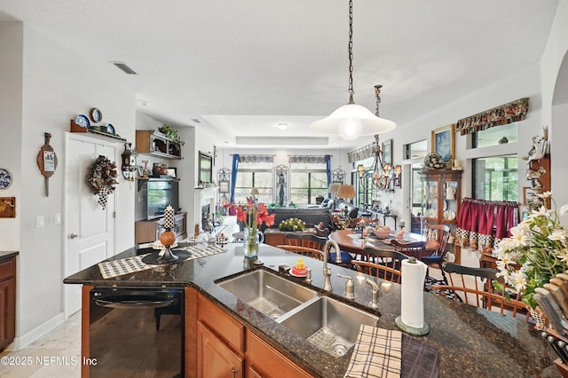 kitchen with dark stone counters, a sink, a healthy amount of sunlight, dishwasher, and open floor plan