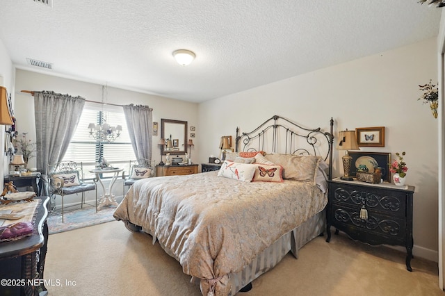 bedroom featuring visible vents, light carpet, and a textured ceiling