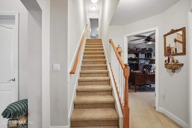 stairs featuring baseboards, ceiling fan, a textured ceiling, and carpet flooring