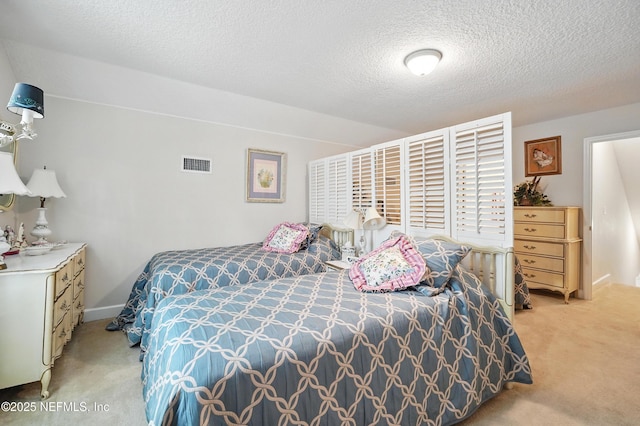 bedroom featuring visible vents, a textured ceiling, and light colored carpet