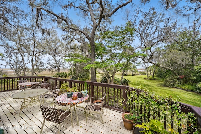 deck featuring outdoor dining space and a lawn