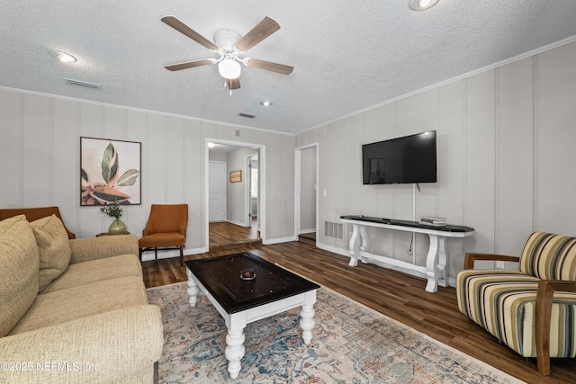 living area with crown molding, ceiling fan, wood finished floors, and visible vents