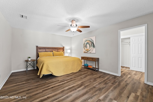 bedroom with a textured ceiling, baseboards, wood finished floors, and visible vents