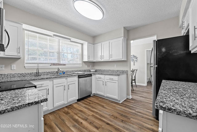 kitchen with stainless steel appliances, a textured ceiling, white cabinetry, and a sink