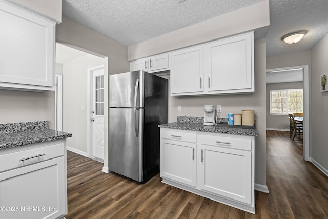kitchen with dark wood-type flooring, freestanding refrigerator, and white cabinetry